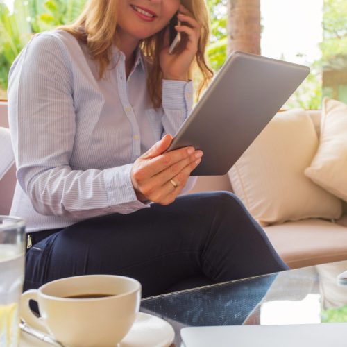 Businesswoman speaking on phone and looking at tablet