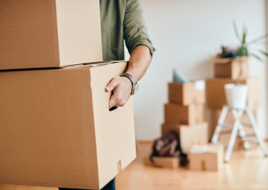 Close-up of a man with carton boxes moving into new home.