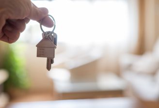 Hand,Holding,House,Keys,With,A,House,Shaped,Keychain,In