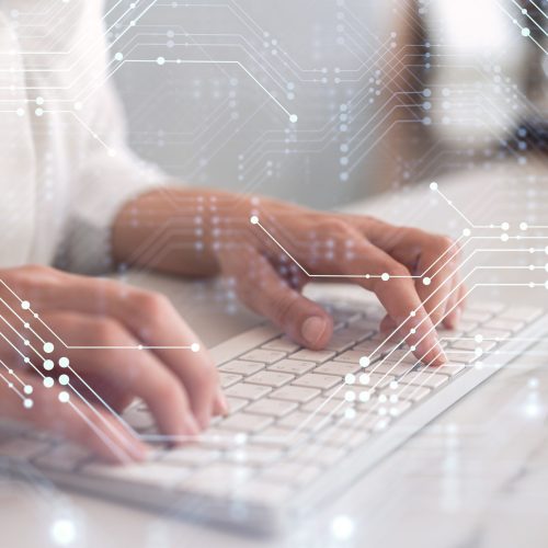 Woman typing the keyboard to create innovative software to change the world and provide a completely new service. Close up shot. Hologram tech graphs. Concept of Dev team. Formal wear.