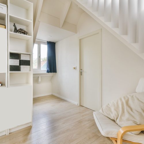 Wonderful soft beige armchair in a cozy room with parquet floor and window